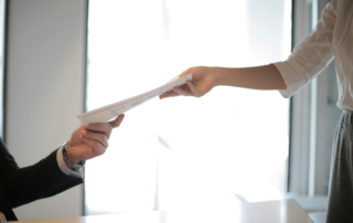 An employee is handing a document to her employer
