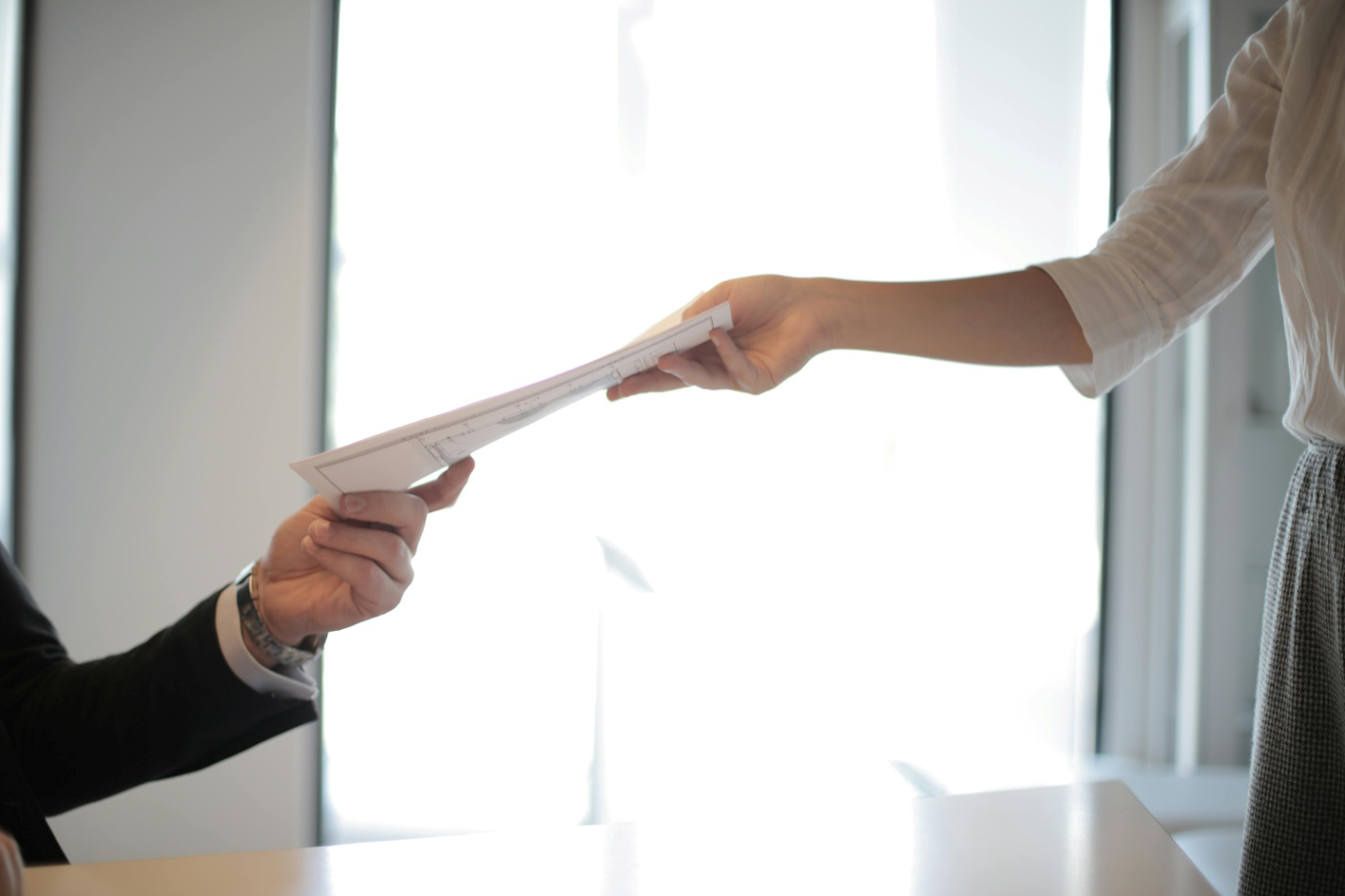 An employee is handing a document to her employer
