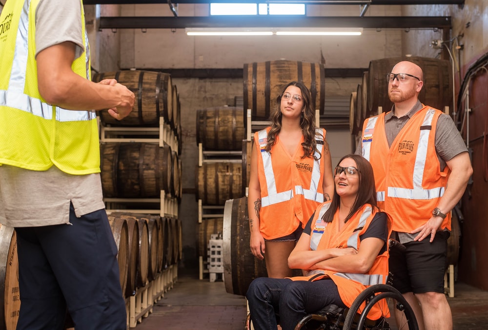 Woman in wheelchair with two workers being guided by employer