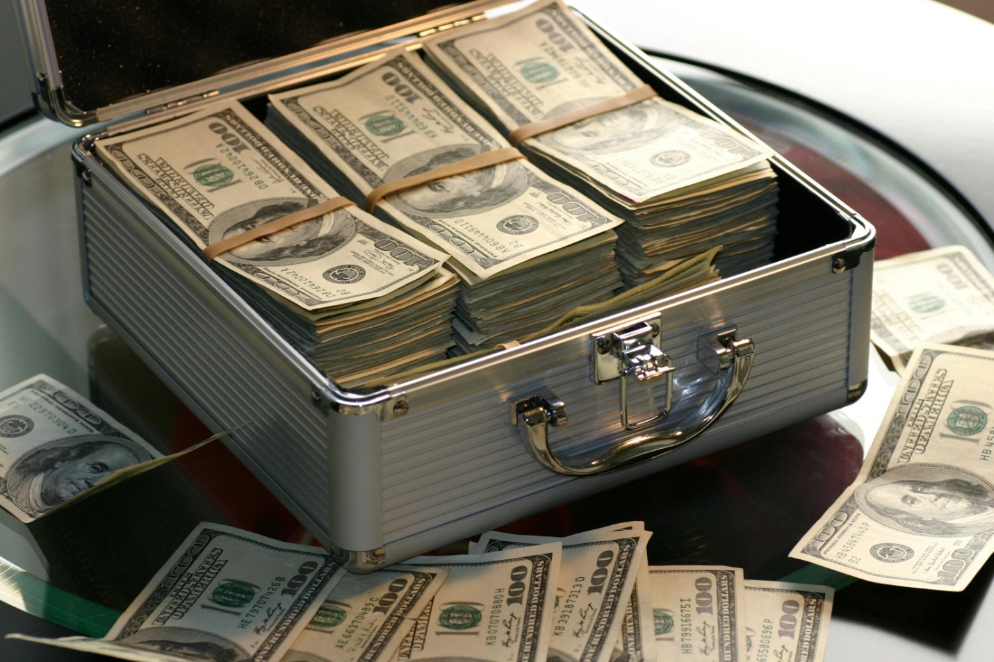 A metal cash lock box filled with hundred-dollar bills 