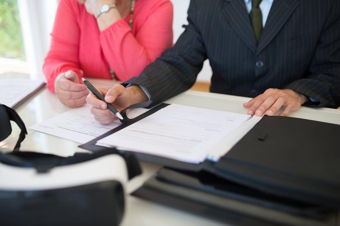 a woman and a man sitting holding a pen going through documents