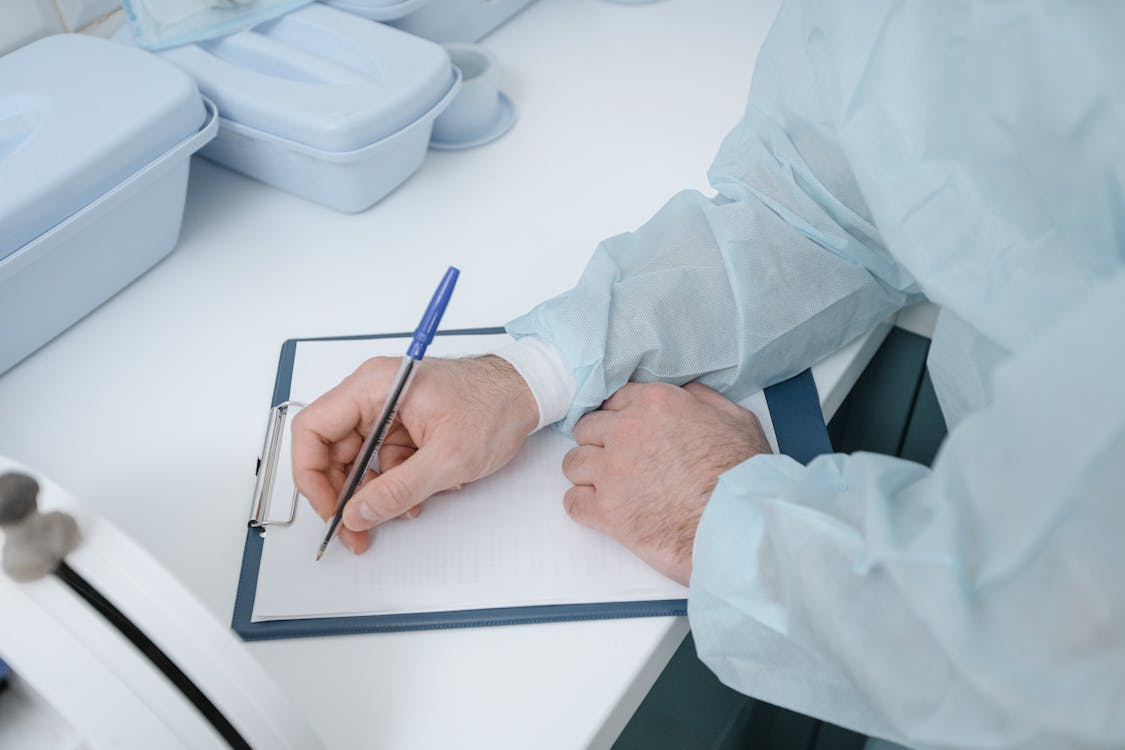 a doctor using a paper on a clipboard and a pen to write down notes