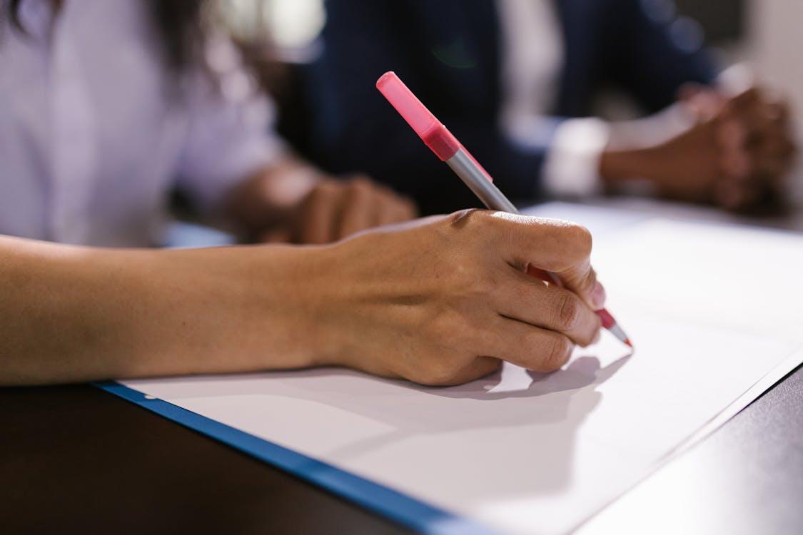 close-up of a person filling a form with a red pen