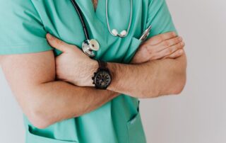 a nurse standing with his arms crossed wearing a stethoscope