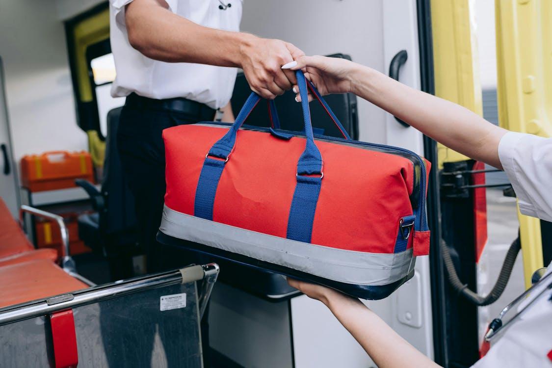 a man and a woman exchanging a paramedic bag through an ambulance