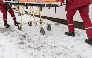 paramedics using a stretcher to carry a patient towards the ambulance