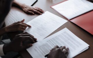 Two people reviewing paperwork, one explaining while the other prepares to sign