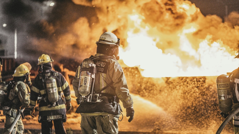 Firefighters standing in front of active flames during a fire response