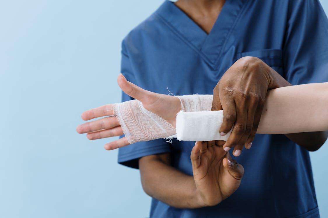 Close-up of a person getting their hand bandaged after a work-related injury