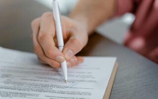 A man is seen signing a legal contract using a pen.