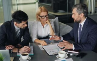 Three people sitting on a table discussing a work injury case together.