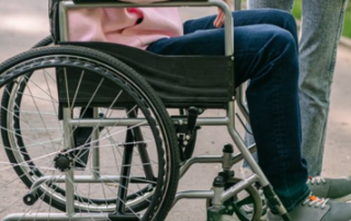 Person in a wheelchair holding the hand of a caregiver following a permanent work-related disability