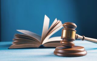 Judge’s gavel striking a sound block with a legal reference book in the background