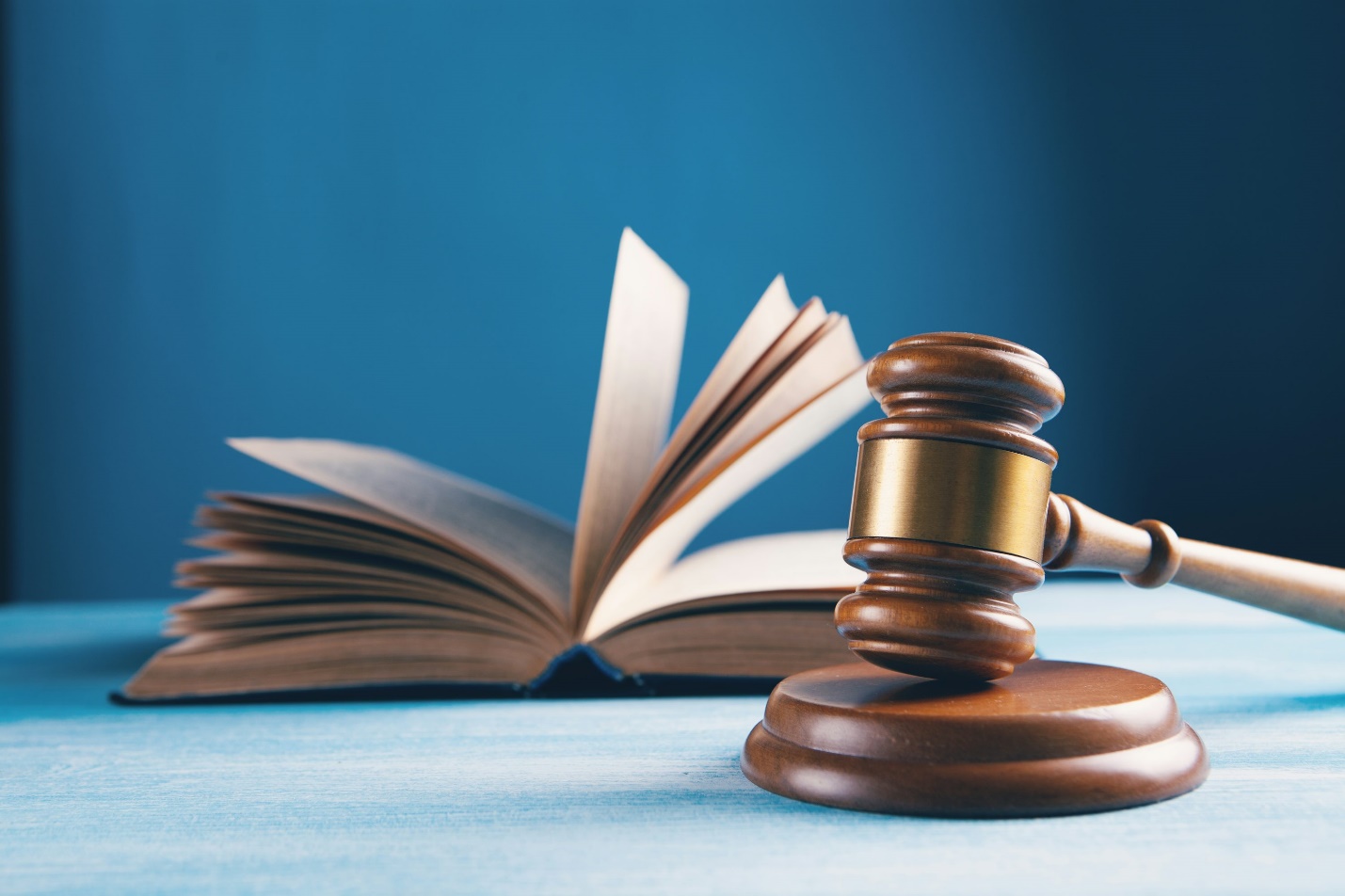 Judge's wooden gavel resting on a desk beside legal documents in a courtroom setting.