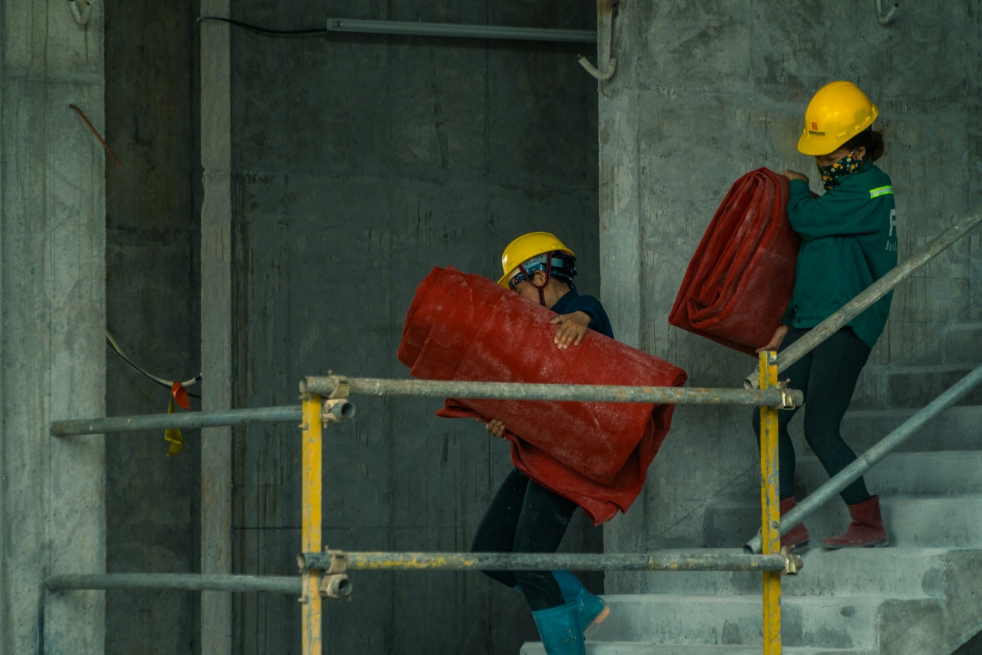 Construction worker performing physically demanding tasks while carrying building materials at an active job site.