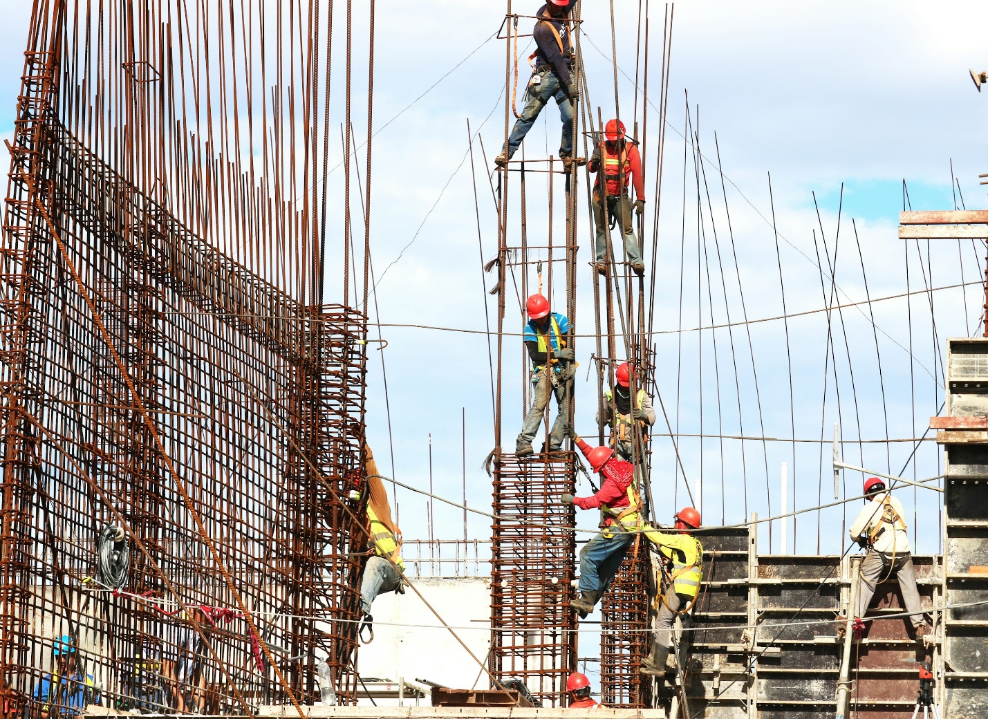 High-risk construction site with heavy machinery, scaffolding, and active workers following safety procedures.