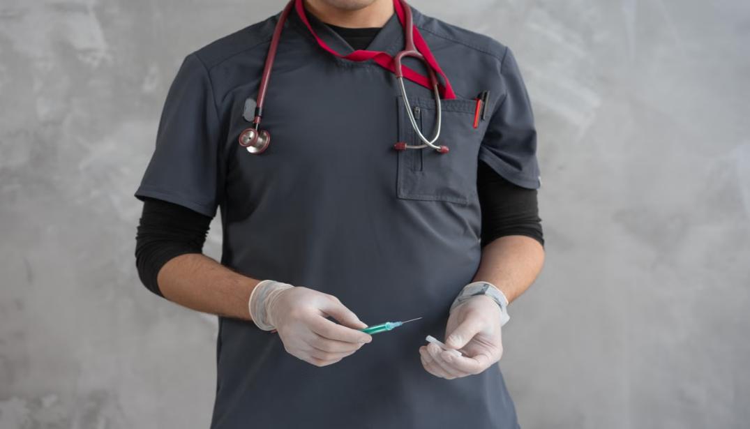 Healthcare worker handling a syringe after a work-related injury.