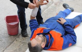 An image of a man lying on the ground receiving first aid treatment